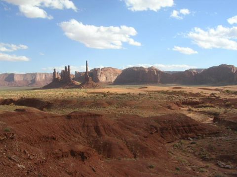 1975 Ford Ranchero - The iconic rock formations of Monument Valley stand tall against a bright blue sky dotted with white clouds.