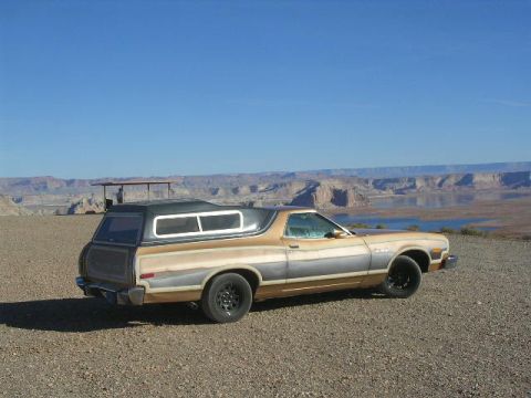 1975 Ford Ranchero - A 1975 Ford Ranchero with a camper shell is parked on a gravelly surface overlooking a vast canyon and lake.