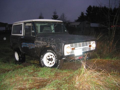 1968 Ford Bronco - This 1968 Ford Bronco appears stuck in muddy ground, with its white wheels and top contrasting against its dark body.