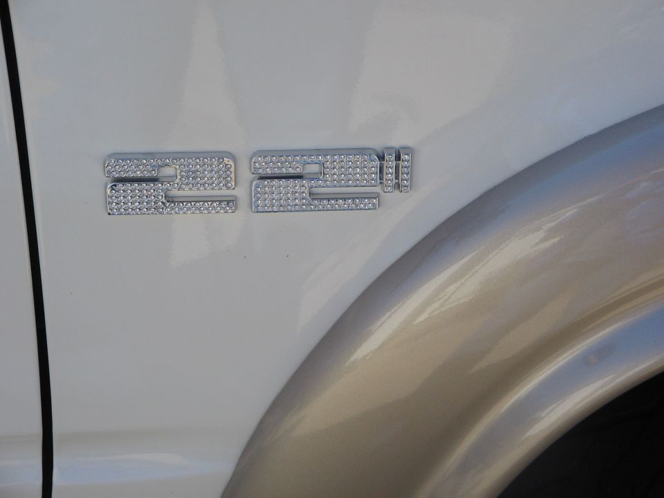 Rhinestone chrome 22-inch badge on white body panel beside gold fender flare