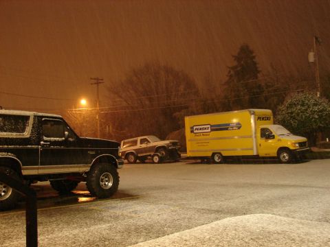 1996 Ford Bronco - A lifted black SUV and a Penske truck are parked in the snow, with a second SUV visible in the background.