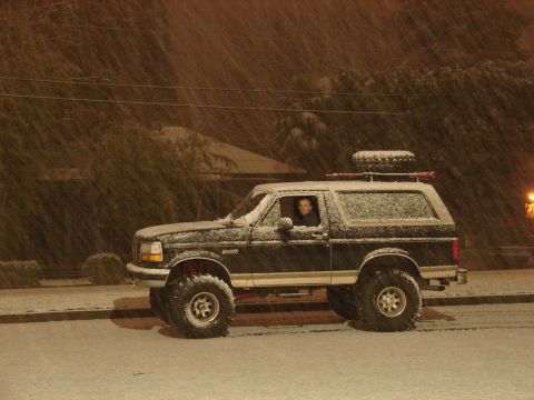 1996 Ford Bronco - A person drives a lifted Ford Bronco through a snowy night scene.