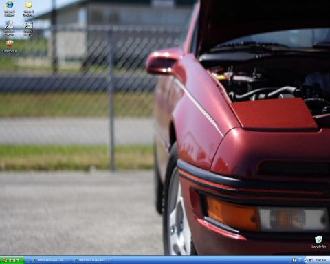 1991 Ford Probe - The front quarter of a red 1991 Ford Probe is shown with its hood open, revealing the engine bay.