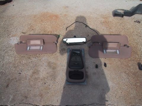 1994 Ford Bronco - Disassembled interior parts including sun visors, overhead console, and rear view mirror on concrete.