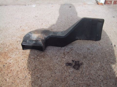 1994 Ford Bronco - A black plastic air intake duct and some screws are shown on a concrete surface.