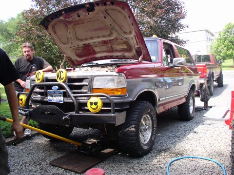 1996 Ford F-250 - A red and gray Ford Bronco is parked with its hood open, while another red truck is visible behind it.
