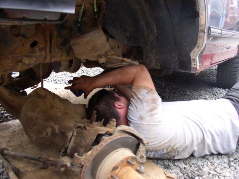 1996 Ford F-250 - Mechanic works on the rear axle assembly of a 1996 Ford F-250 truck.