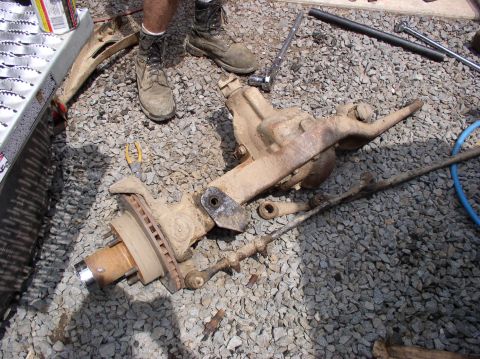 1996 Ford F-250 - Truck front axle and steering parts laid out on the ground for repair or replacement.