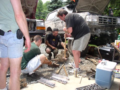 1996 Ford F-250 - Multiple people are gathered around a truck's drivetrain, appearing to be in the middle of repairs or modifications.