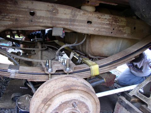 1996 Ford F-250 - A mechanic works on the undercarriage of a truck, focusing on the suspension and fuel tank components.