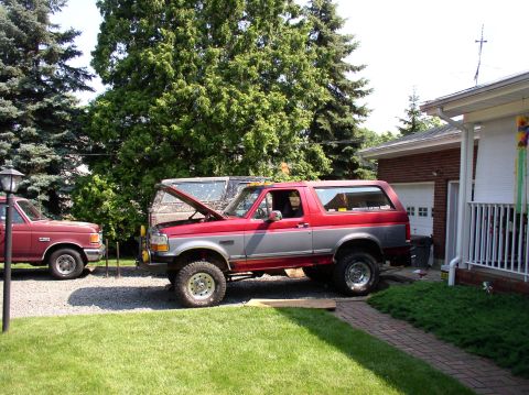 1996 Ford F-250 - Two trucks are parked in a driveway on a sunny day, one with its hood open.