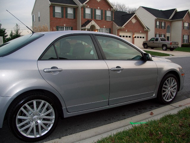 Silver sedan parked on street, houses in background