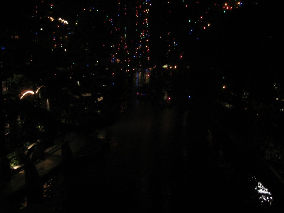 Dark night view of a riverwalk with colorful lights reflecting on water
