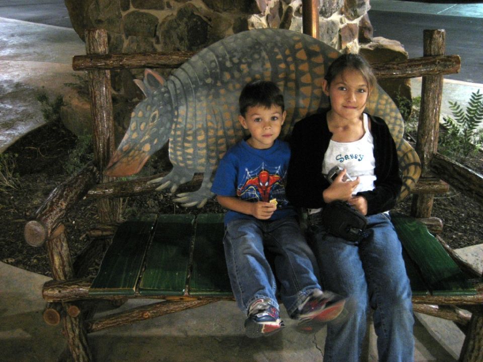 Two people sit in front of a vintage SUV, possibly a 1980s model