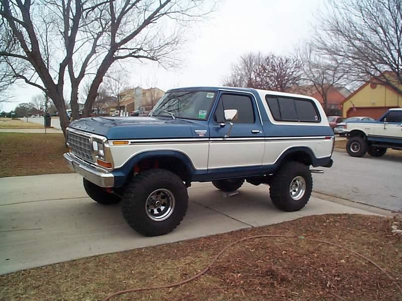 Blue and white lifted late-1970s Ford Bronco parked on a residential driveway