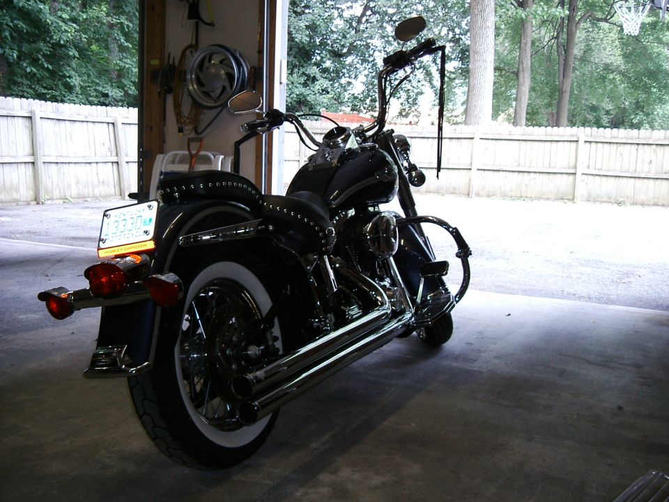 2003 Harley-Davidson Softail motorcycle parked in a garage, rear view. Whitewall tire and chrome exhaust visible