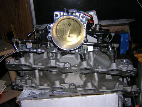 1979 Ford Bronco - Close-up of an engine's intake manifold and throttle body, showing fuel injectors and associated wiring.