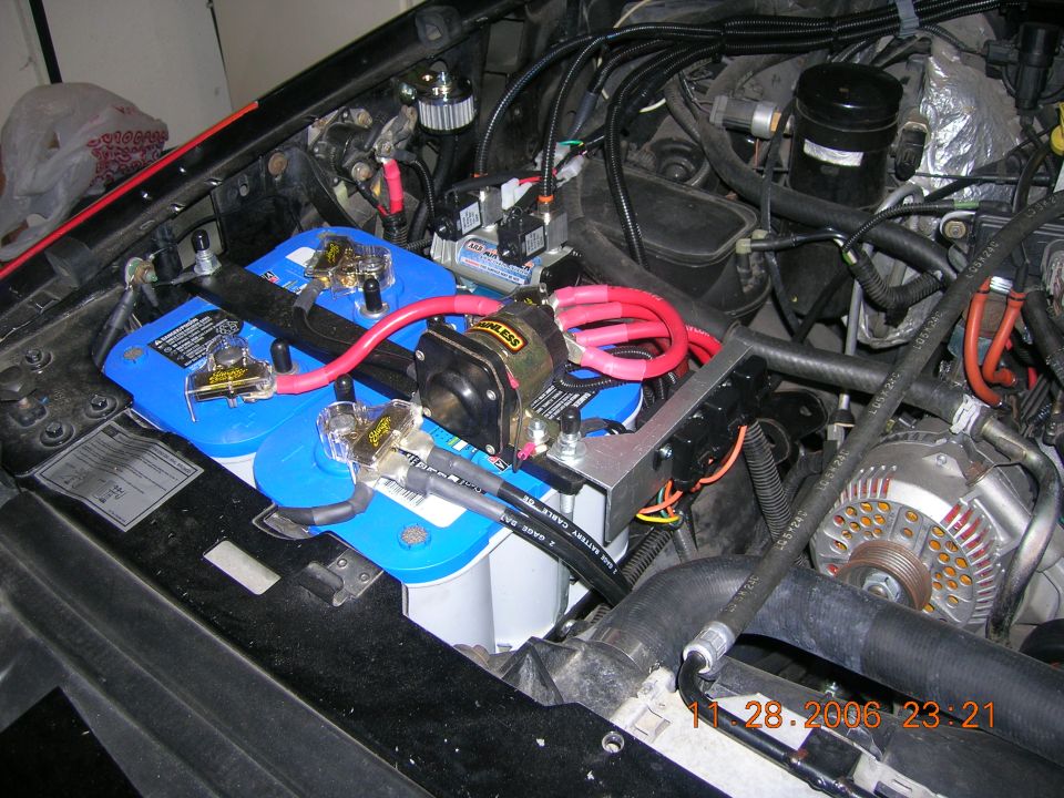 Dual blue-top batteries with gold terminals and onboard air compressor in an engine bay