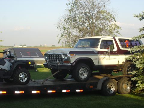 1979 Ford Bronco - A two-tone Ford Bronco and an ATV are transported on a flatbed trailer.