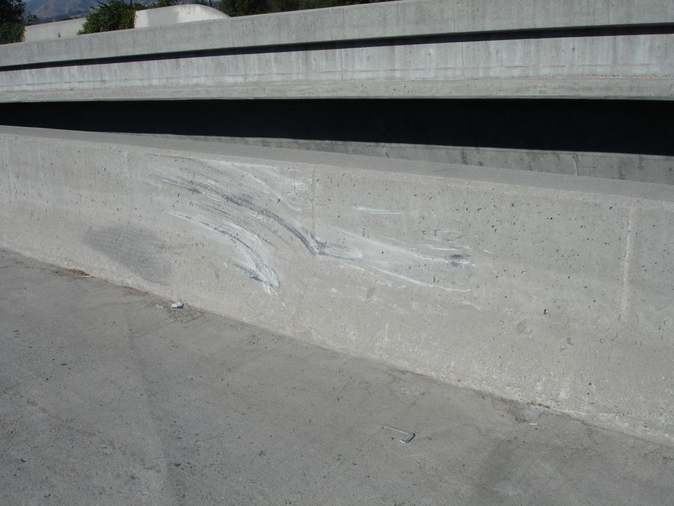 Concrete barrier on an overpass with white and grey scrape marks