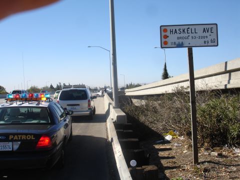 1993 Ford Taurus - Traffic is stopped on a freeway overpass, with a police car in the foreground and a sign indicating Haskell Ave.