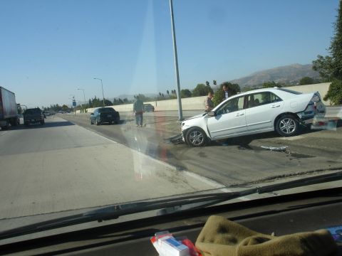 1993 Ford Taurus - A white sedan is involved in a highway accident, with visible damage to its front and rear.