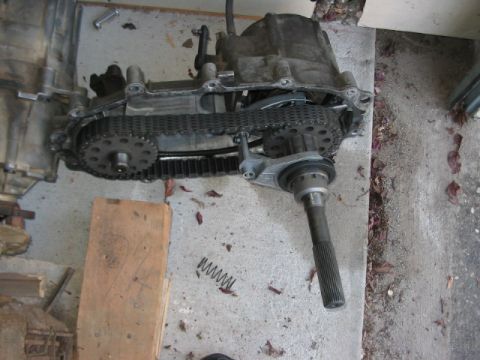 1991 Ford Bronco - Transfer case assembly with visible chain and sprockets, resting on concrete.
