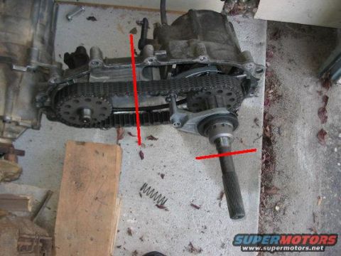1995 Ford Bronco - A disassembled transfer case sits on a concrete surface, showing its internal chain and gears.