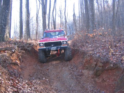 1979 Ford Bronco - This modified 1979 Ford Bronco navigates a steep, wooded trail with large off-road tires and a winch.