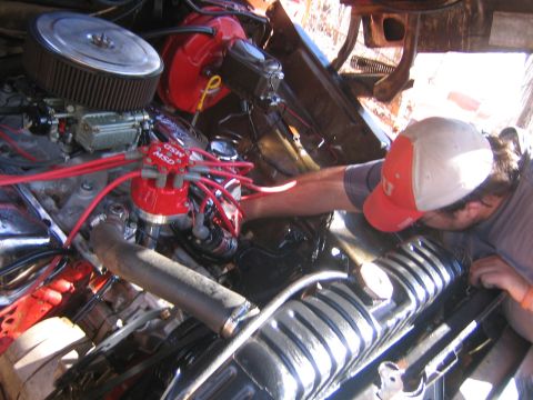 1979 Ford Bronco - Close-up of a vehicle's engine bay, showing a person working on the engine components.
