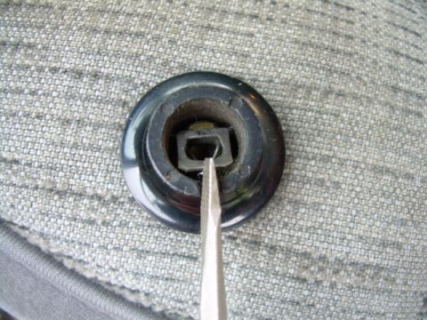 1988 Ford Bronco - Interior trim piece with a square hole, possibly for a knob or switch, being worked on with a screwdriver.