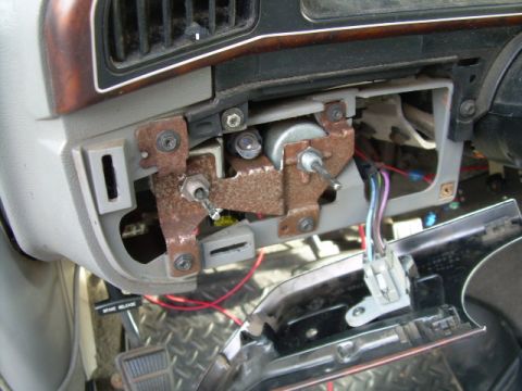 1988 Ford Bronco - The dashboard wiring harness of a 1988 Ford Bronco is visible, with a rusty bracket and disconnected electrical components.