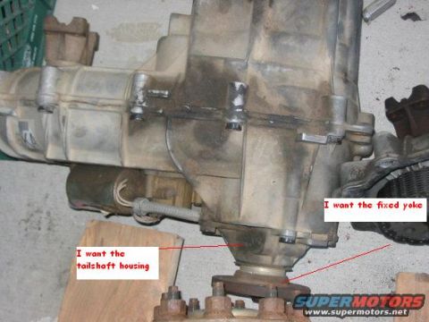 1992 Ford Bronco - transmission or transfer case sitting on wood blocks with red annotations pointing to the tailshaft housing and fixed yoke.