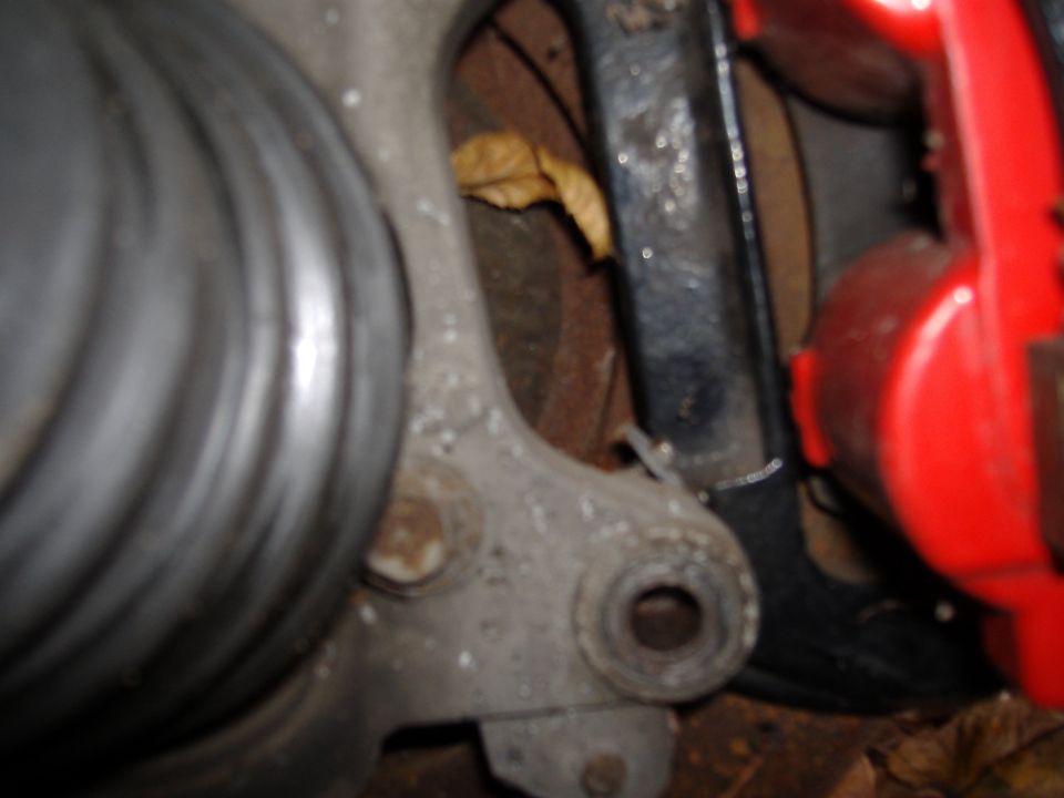 Close-up of a car's suspension component with a red brake caliper visible