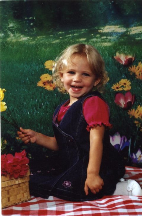 1976 Ford F-150 - A smiling child sits on a picnic blanket, holding a small bouquet of flowers.