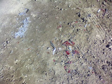 1995 Ford Bronco - The ground is covered in dirt and debris, with visible tire tracks suggesting vehicle passage.