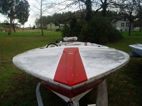 1978 Ford F-250 - The front of a white and red boat is shown on a trailer in a grassy area with trees and houses in the background.