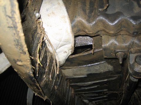 1995 Ford Bronco - Mud and debris cover the underbody of a vehicle, obscuring specific details.