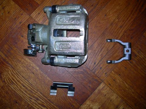 1992 Ford Taurus - A Ford brake caliper, clearly marked with Ford and Motorcraft branding, is shown with associated hardware on a wooden surface.