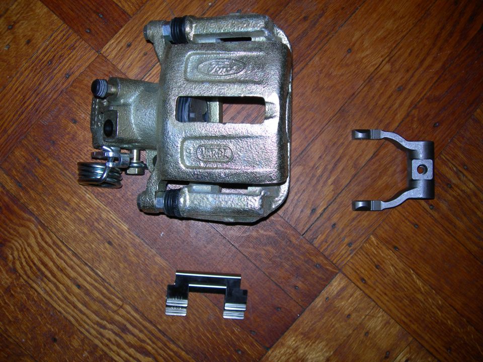 Ford brake caliper with "Ford" and "Motorcraft" logos, alongside mounting hardware