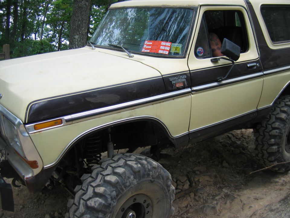 Yellow and brown Ford Bronco with off-road tires on rocky terrain