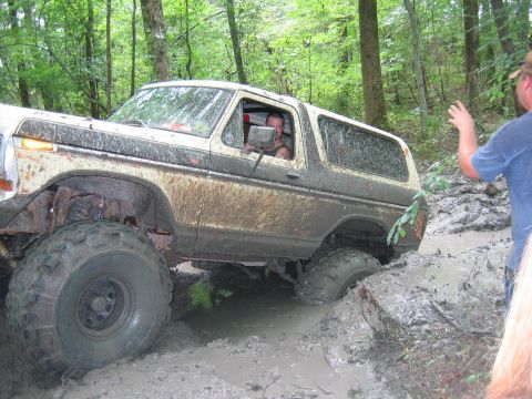 1992 Ford Mustang - A heavily modified Ford Bronco navigates a muddy off-road trail, getting stuck in deep mud.