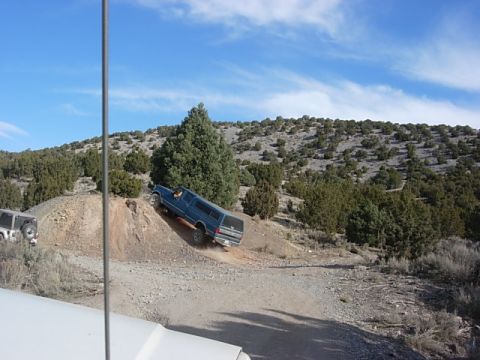 1987 Ford Bronco - Blue 1987 Ford Bronco with camper shell navigates an off-road trail with another vehicle nearby.
