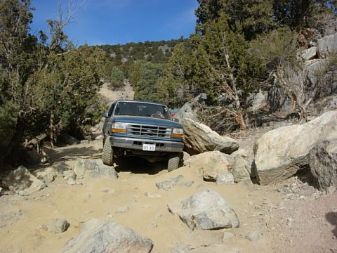 1987 Ford Bronco - This Ford Bronco is navigating a challenging rocky terrain on a sunny day.