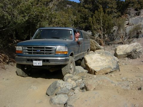1987 Ford Bronco - This blue Ford F-Series truck, likely a 1992 model, navigates a challenging rocky terrain with a camper shell installed.