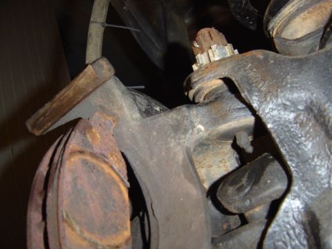 1986 Ford Bronco - Close-up view of a heavily rusted brake caliper and rotor assembly, showing significant wear and tear.