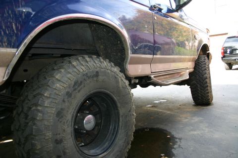 1996 Ford Bronco - A blue Ford Bronco with aftermarket modifications is parked outside.