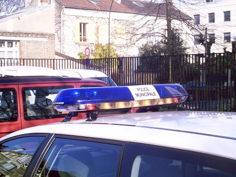 1991 Ford Crown Victoria - A white police car is seen from the side, equipped with a blue light bar that reads "POLICE MUNICIPALE".