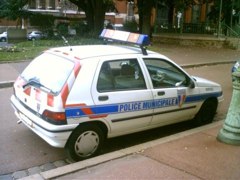 1991 Ford Crown Victoria - A French municipal police car is parked curbside, equipped with a light bar on its roof.