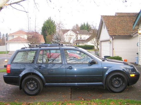2005 Volkswagen Jetta - Side view of a dark blue station wagon parked in front of a house and garage.